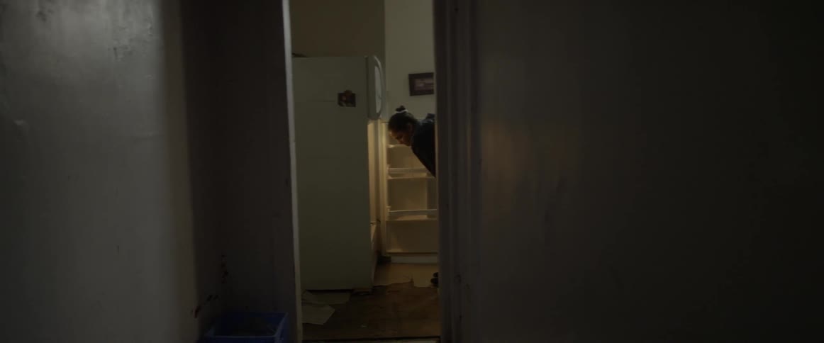 A woman is looking through an empty refrigerator