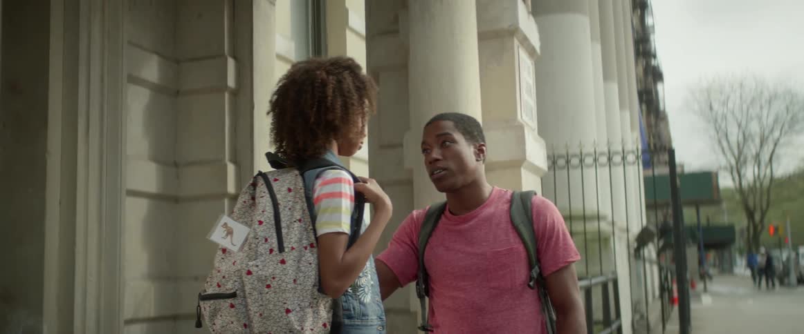 Young man talking to a little girl wearing a backpack outside