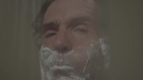 Man shaving his face in the shower