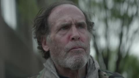 An old man is standing outside and he looks up