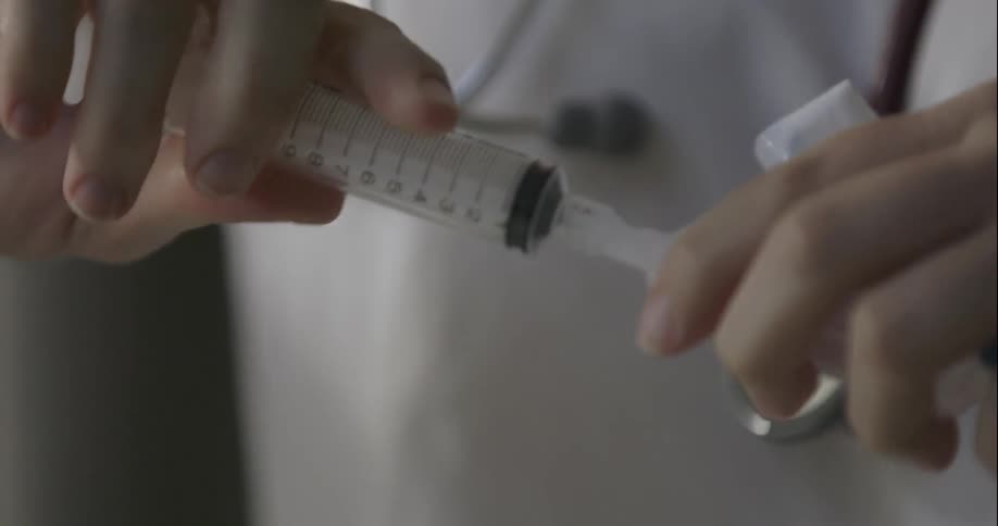 A nurse assembles a syringe