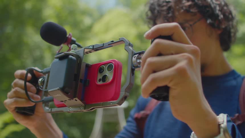 A close up of a person filming with a phone installed over a specialized rig