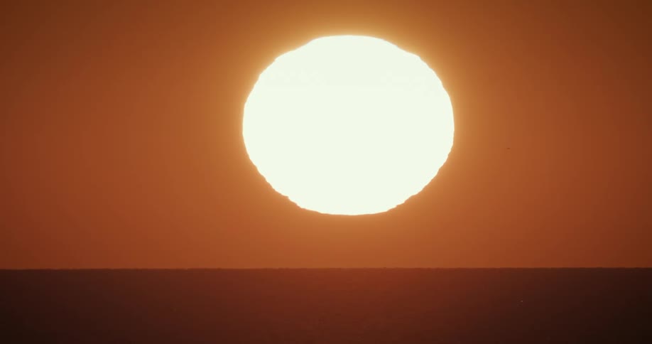 The bright sun rises over a horizon