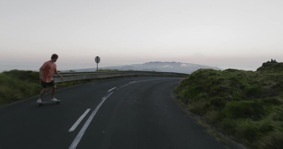 A teenage boy skateboards on a rural road