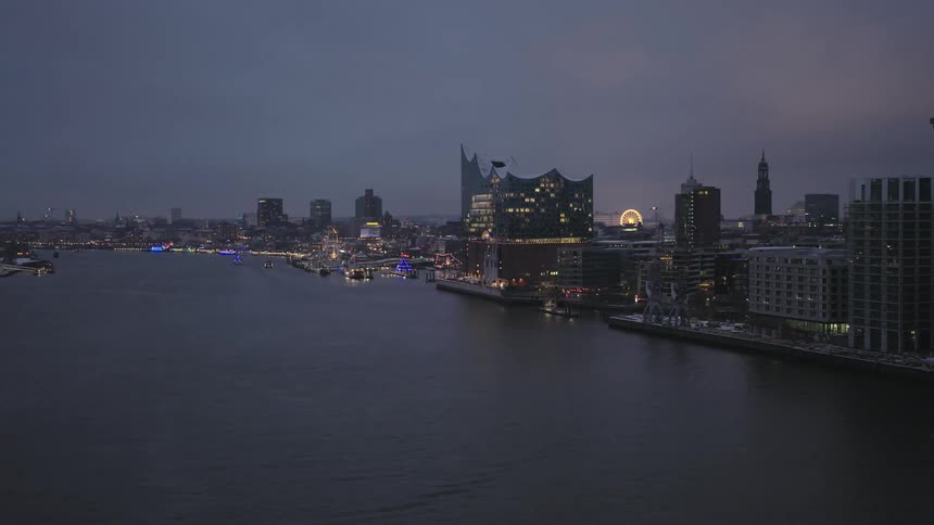 Aerial view of a brightly lit metropolis at dusk on the edge of a sea canal