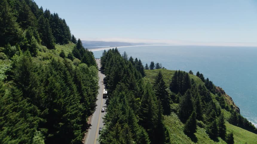 Aerial panorama of a highway on a mountain surrounded by greenery and by the sea