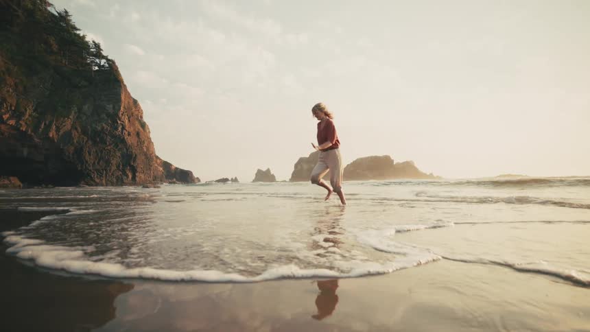 A woman is running through the water on the beach