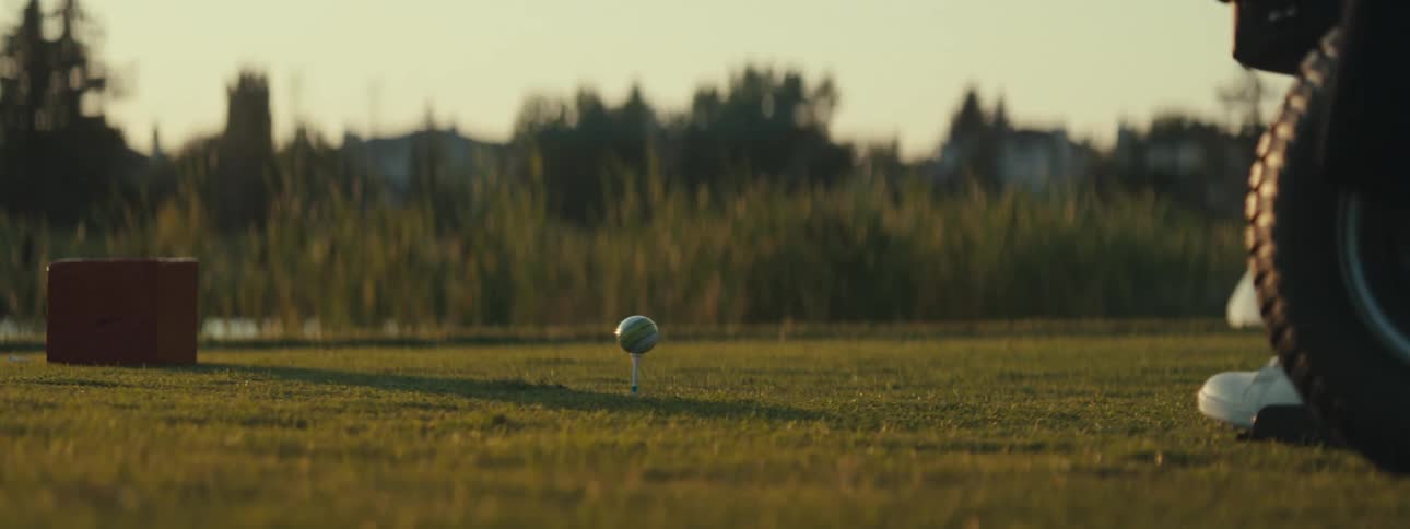 Club hitting a golf ball on a course in the late afternoon