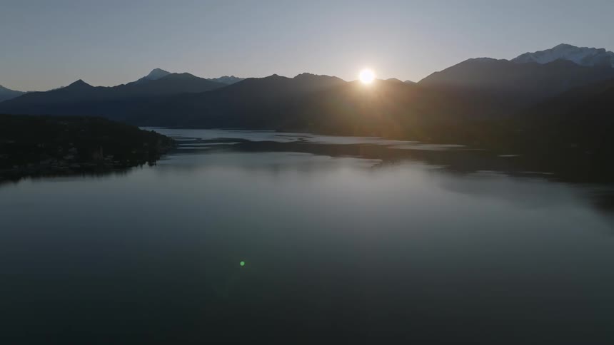 Landscape of a calm lake with the sun rising over mountains