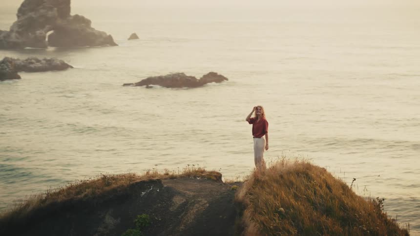 Woman on top of a hill by the ocean