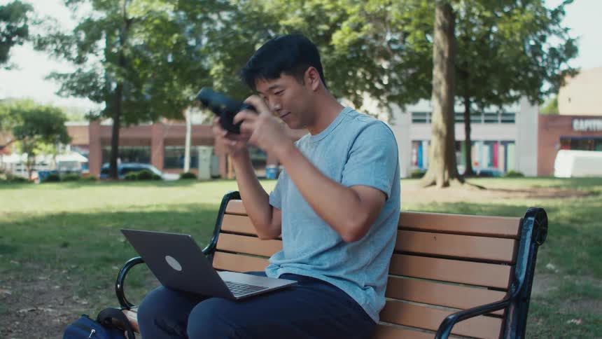 A man opens his laptop in the park