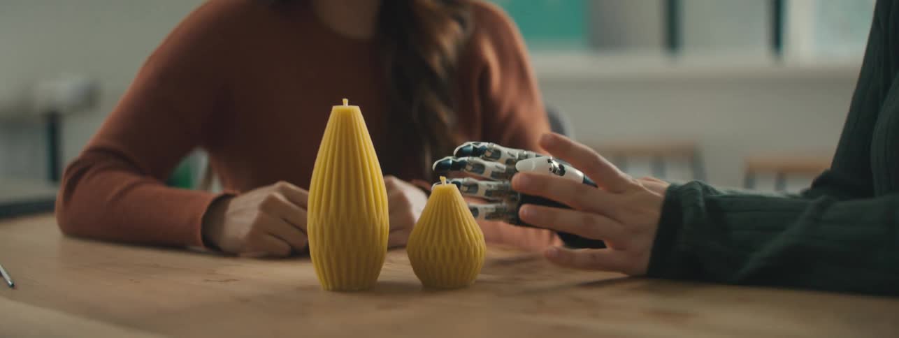 A person waves their prosthetic hand around an item