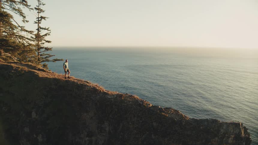 A man walking down a cliffs edge towards the sea