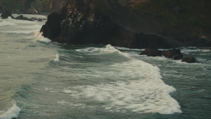 A solitary figure stands on a rocky promontory overlooking a vast ocean