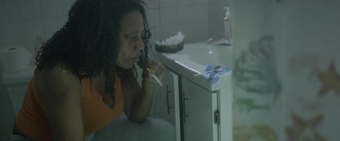 A woman sitting in the bathroom lighting a cigarette