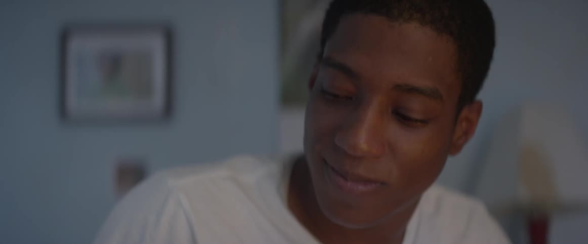 A young man in a white shirt shakes someone and smiles
