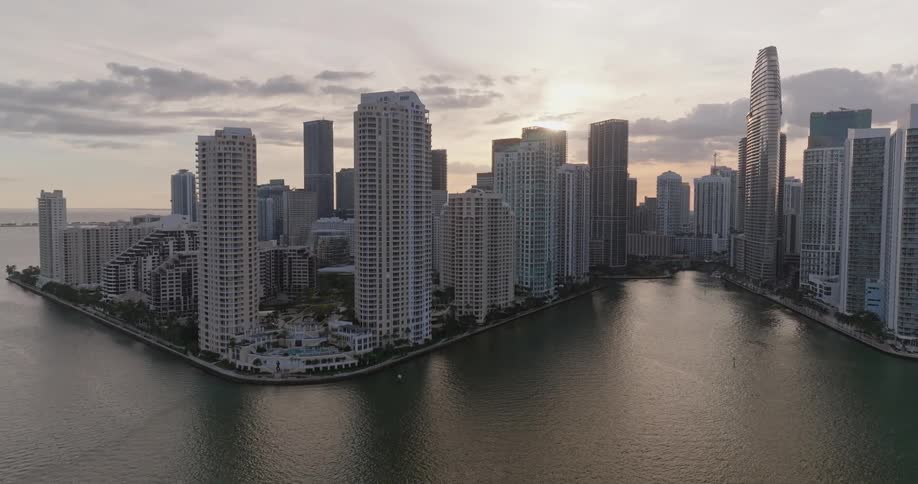 Aerial panorama of a metropolis with skyscrapers on the seafront and the sun on the horizon