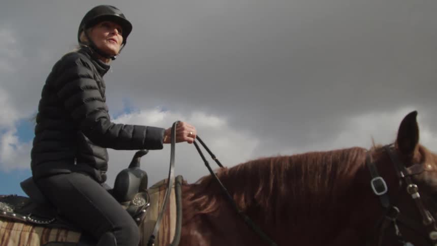 Woman in helmet riding horse
