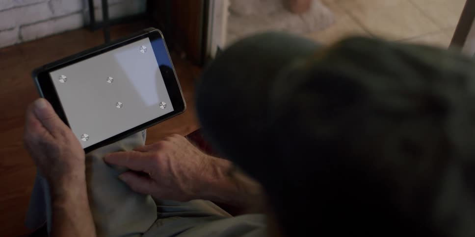 Elderly man sitting holding a tablet and interacting