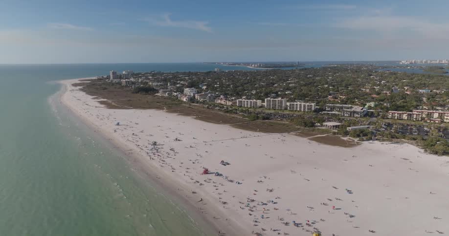 Aerial view of a beach with a long stretch of sand and an urban city in the background