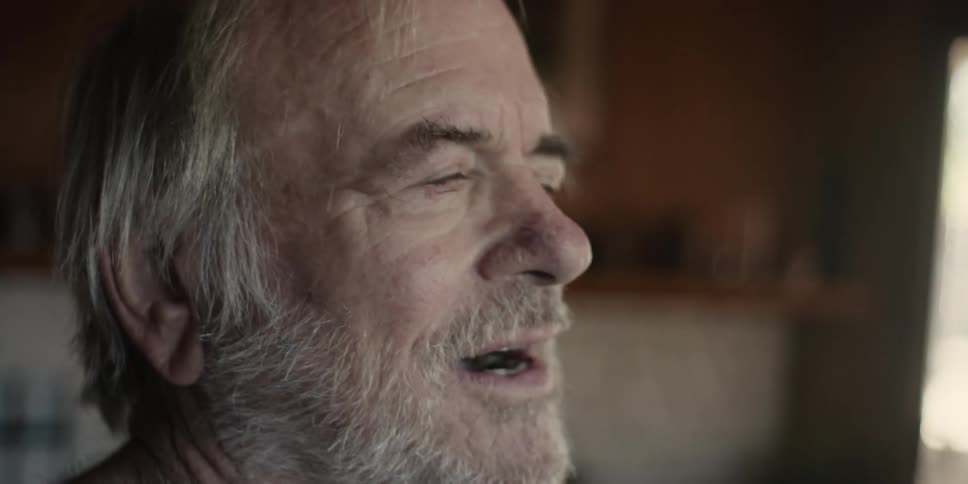 An elderly man smiles while making an effort