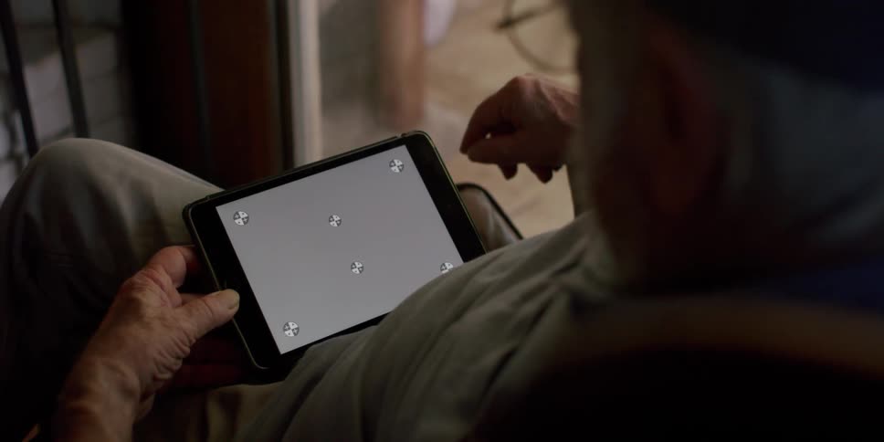 Elderly man sitting in an armchair interacting with the tablet