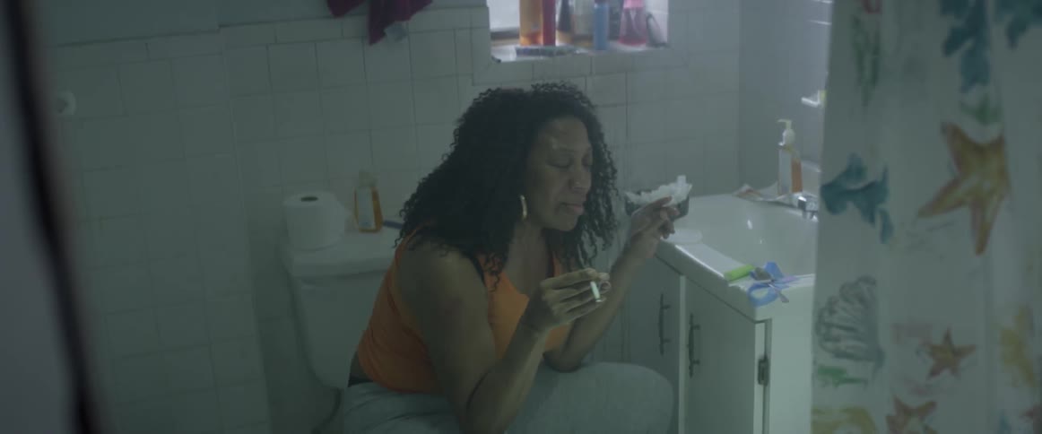 Disheveled looking woman smoking a cigarette in a bathroom