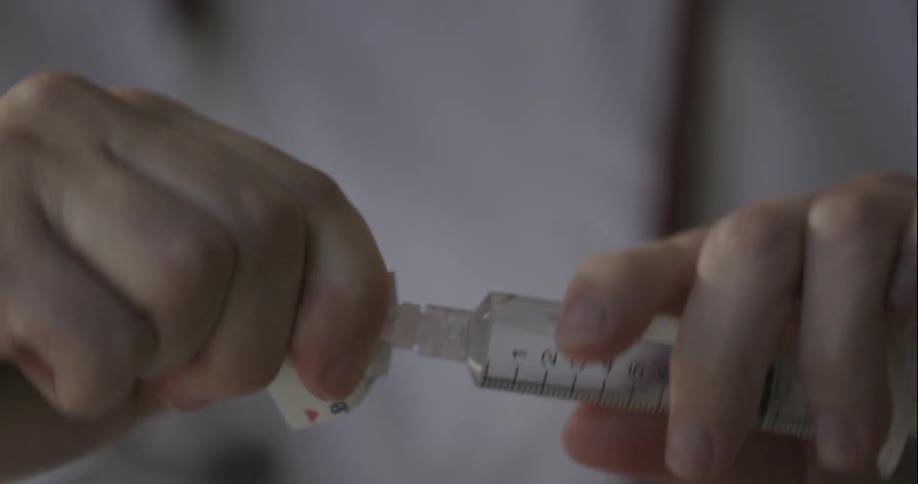 A nurse is attaching a needle to a shot vial