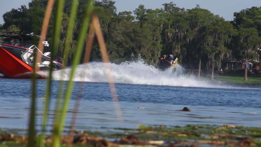 A man skis and flips behind a speeding boat