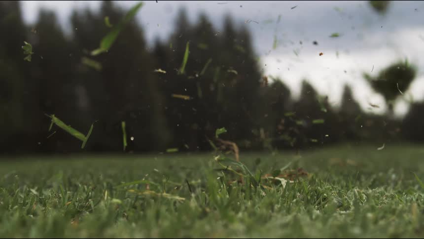 Metal club throwing a golf ball and grass flying through the air