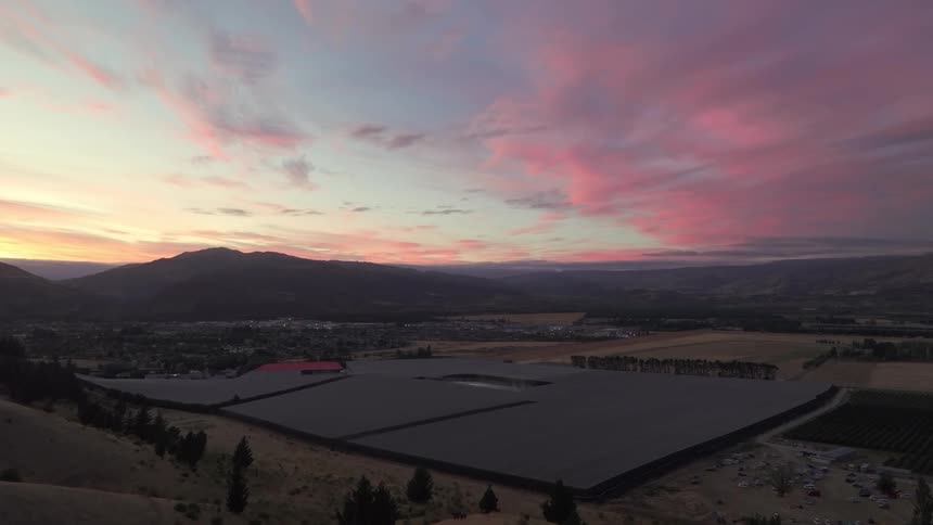 Landscape at dusk with a colorful sky and large agricultural fields below