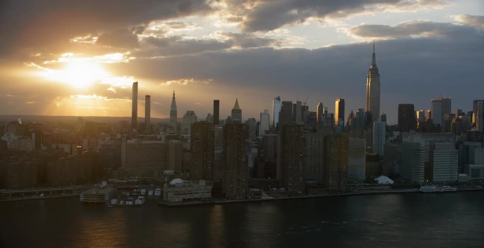 Sun setting behind clouds over large city
