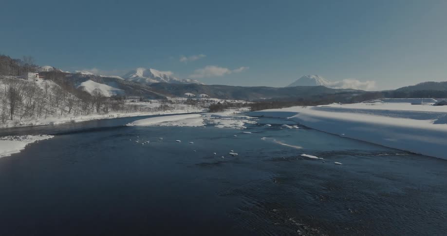 A river with floating ice surrounded by snowcovered banks and hills