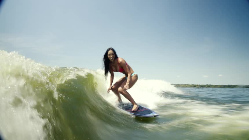A woman is surfing through the waves