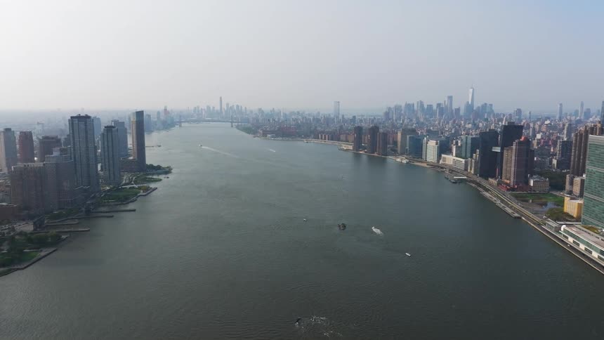 Aerial view of new york city skyline with numerous highrise buildings beside the hudson river boats visible on the water