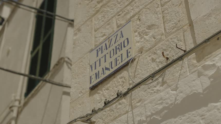 A sign on a white stone wall that says piazza vittorio emanuele