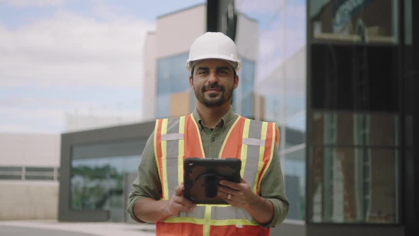 Man in helmet and vest working on a tablet
