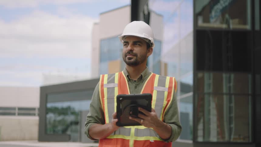 Worker man with protective helmet interacting with a tablet