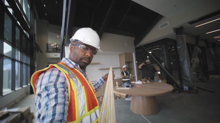 Worker operating a machine and checking a wooden slat