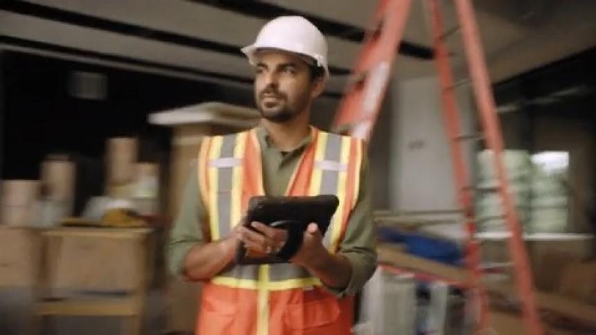 Worker wearing a helmet interacting with a tablet at a construction site