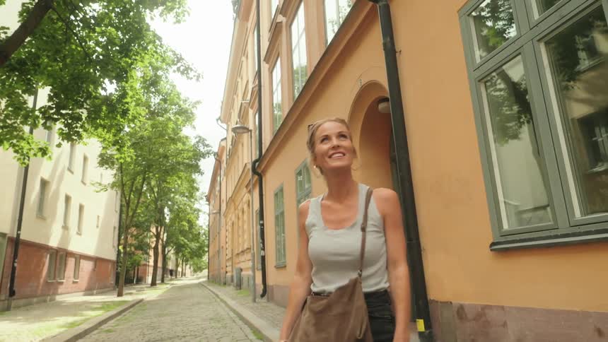 Woman with happy facial expression walking through a classic urban city