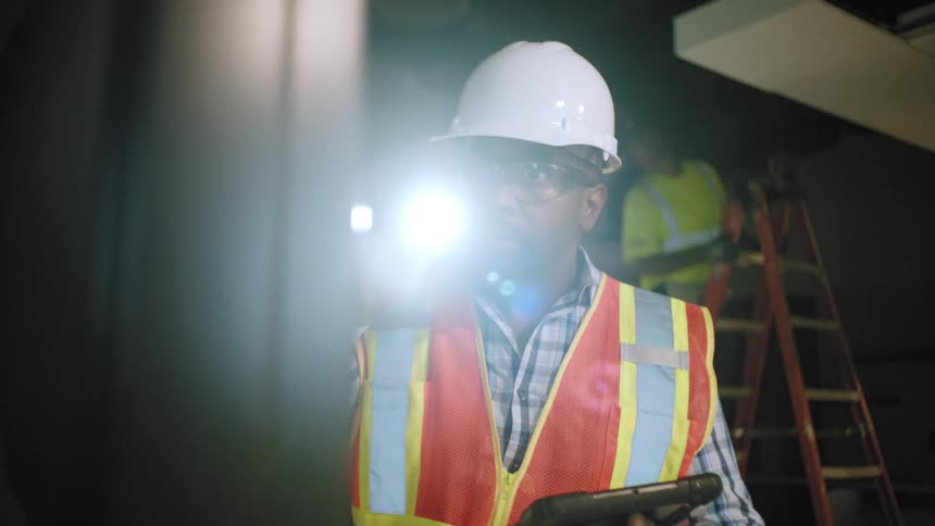 A worker is using a flashlight on the site