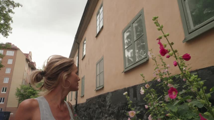 Woman looking at flowers in a flowerbed of a building