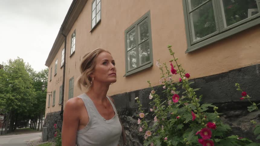 Blonde woman walking next to a flower bed