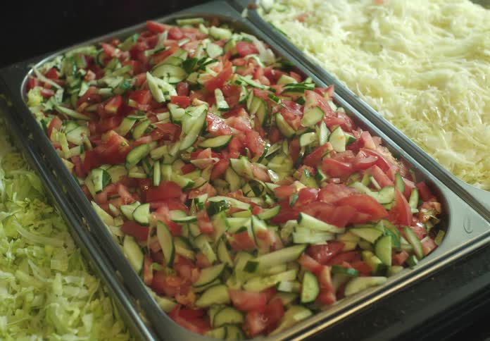 Hand with a specific spatula picking up salad