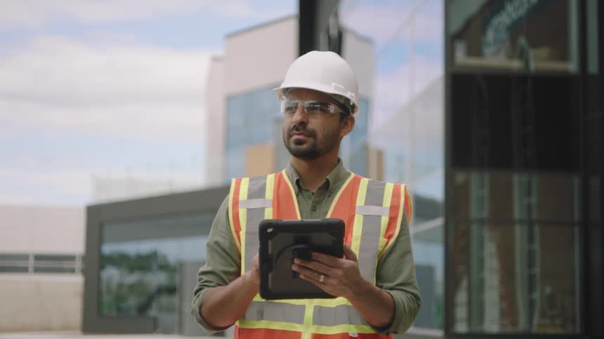 Worker with protective helmet interacting with a tablet