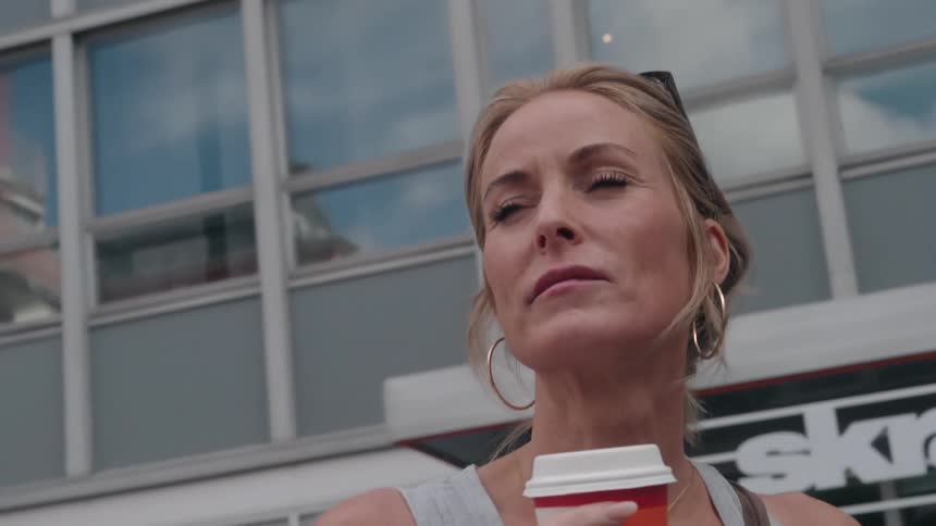 Portrait of a woman in an outdoor setting drinking a drink from a colorful disposable cup