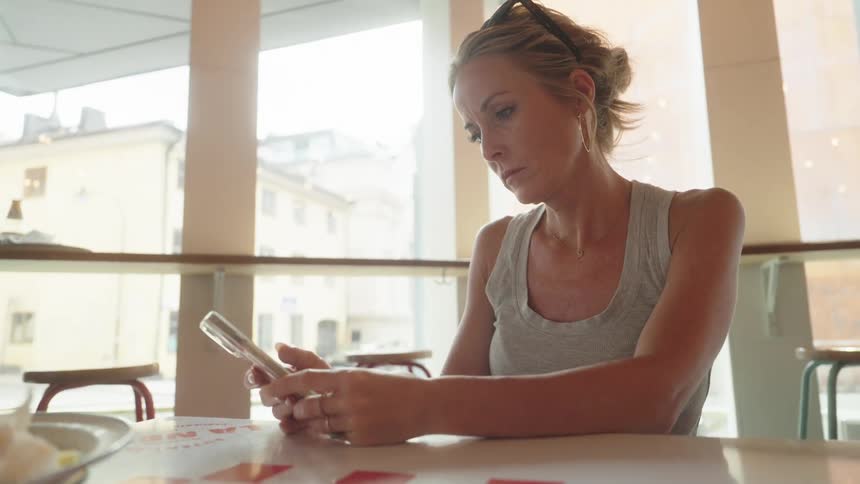 Blonde woman sitting using smartphone