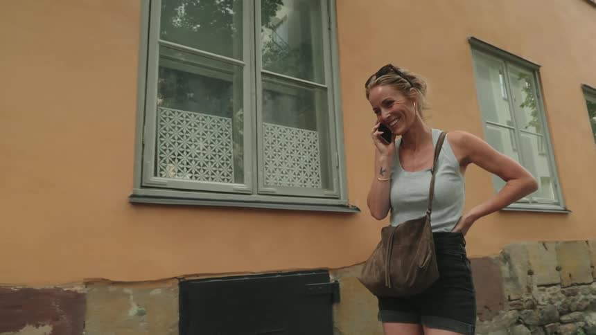 A woman walks down the alley while talking on her cell phone