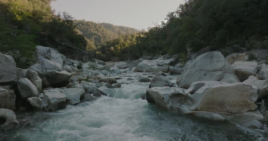 River flowing between rocks with mountains and forests around